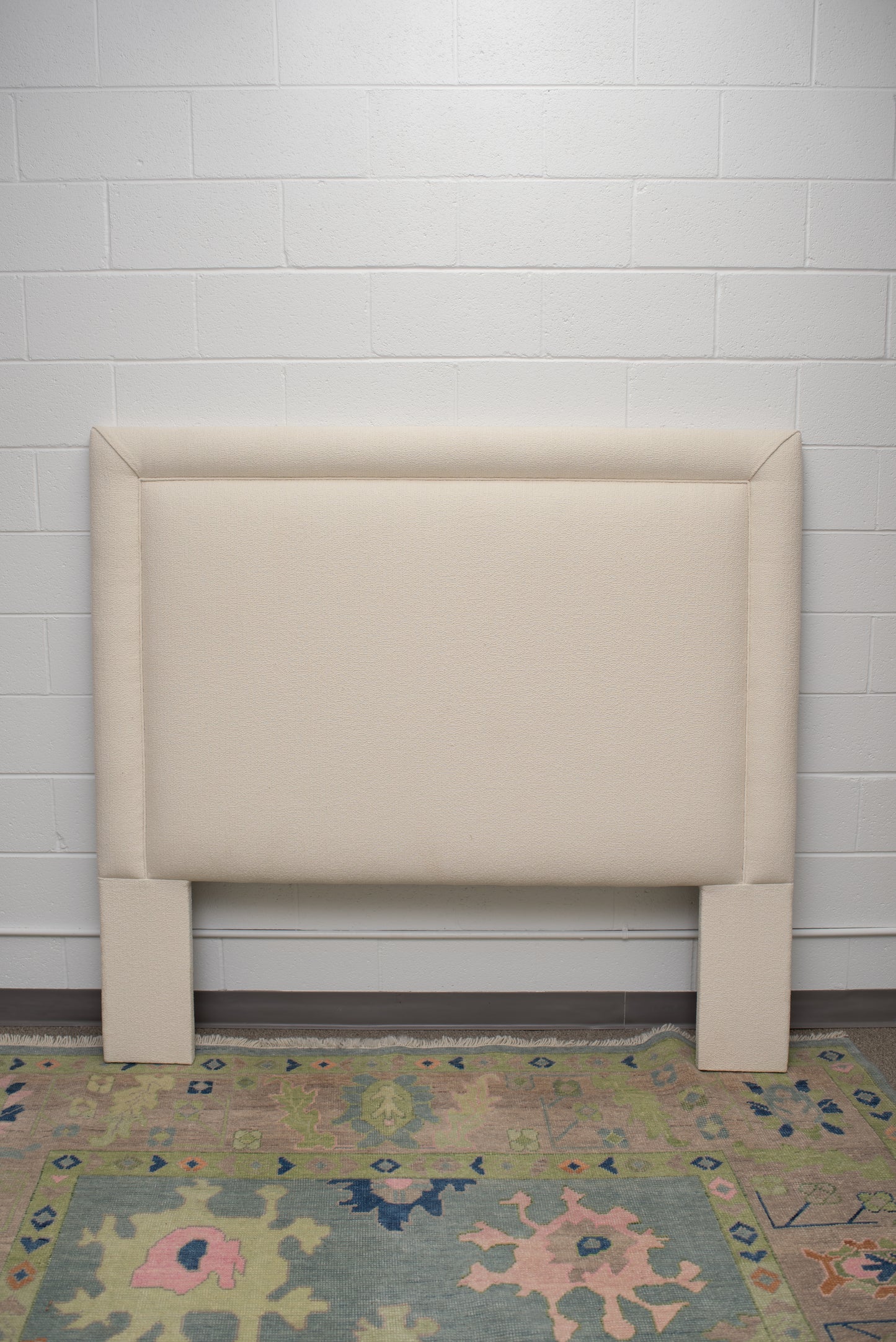 Queen upholstered headboard upholstered in an off white fabric by Winston's Collection.