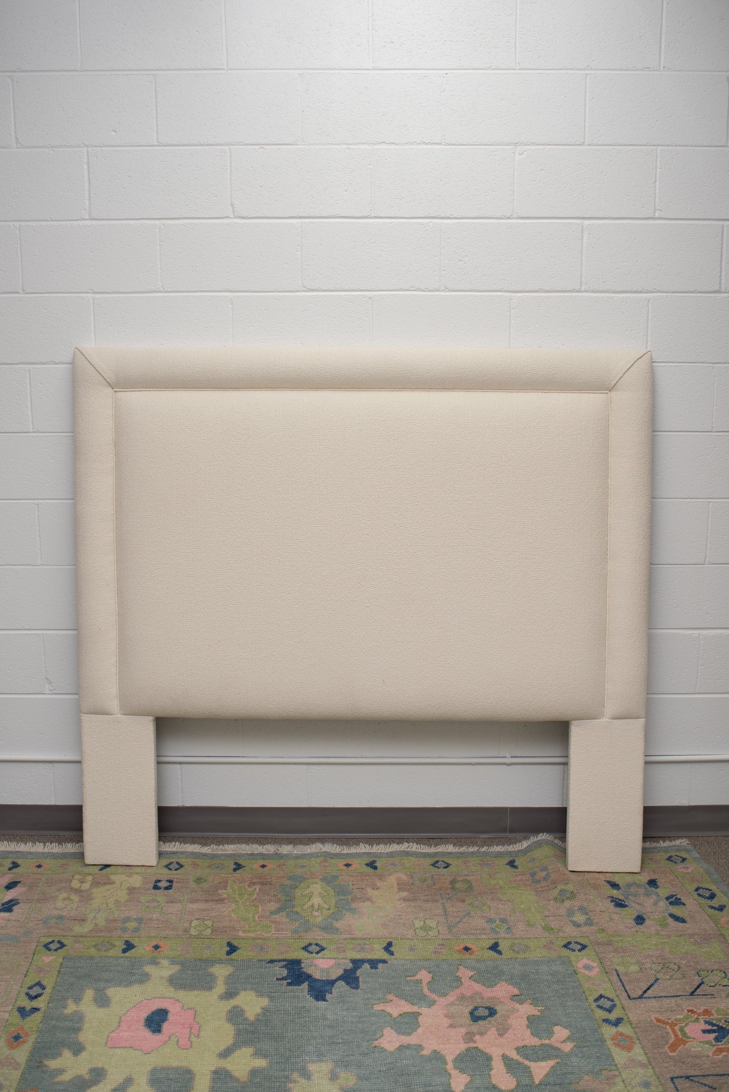 Queen upholstered headboard  upholstered in an off white fabric by Winston's Collection.