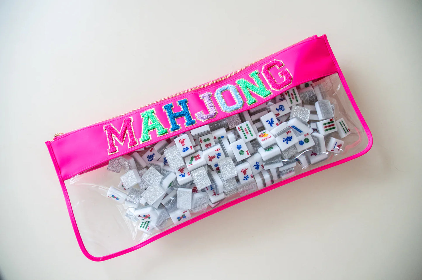a zippered Hot Pink lined clear bag filled with Mahjong tiles with colorful letters reading MAHJONG.