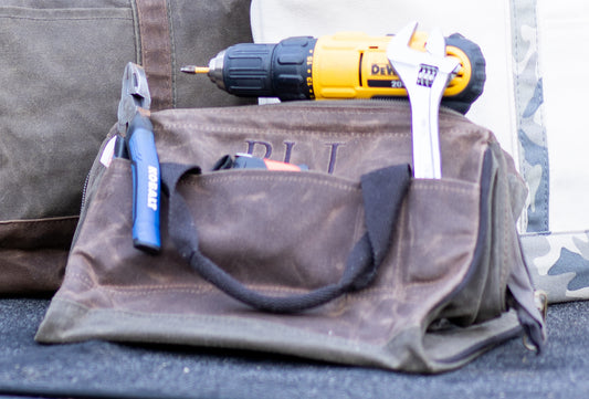 Waxed tool bag pictured with tools and yellow drill embroidered by Winston's Collection