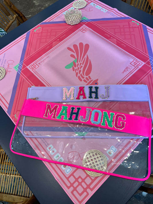 Pink purple and green Mahjong mat with  a purple and clear bag with the letters MAHJ and hot pink and clear bag with the letters MAHJONG.