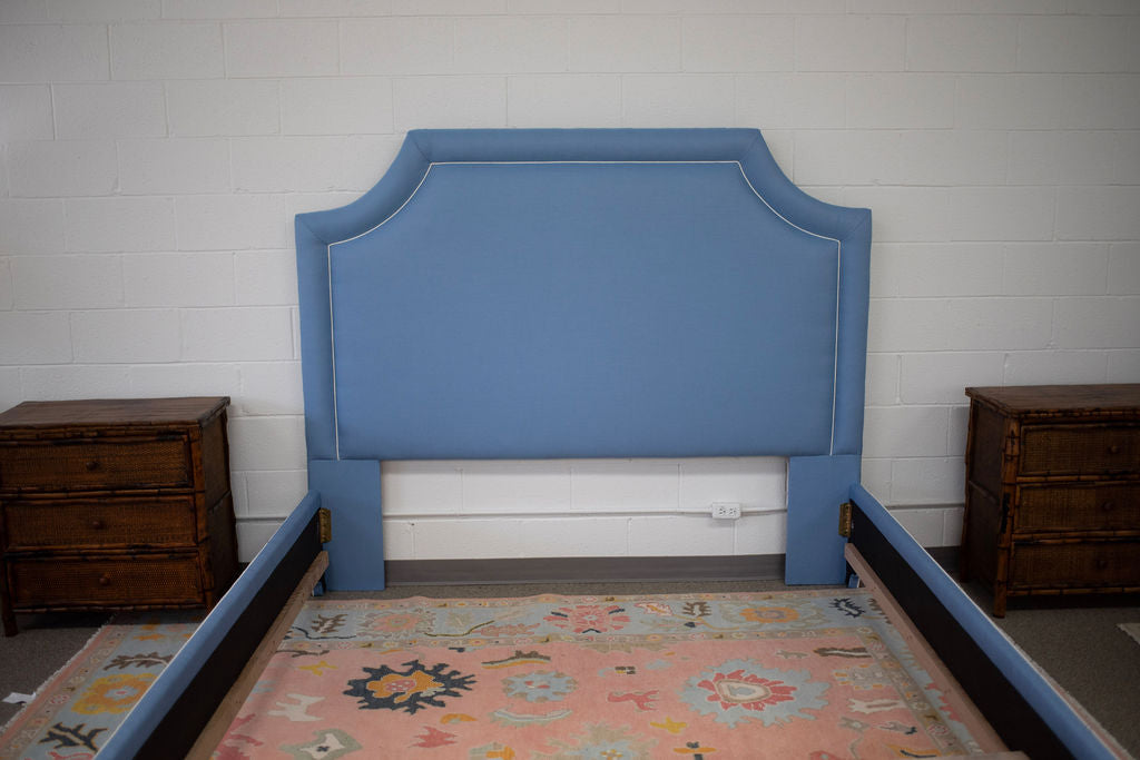 King bed upholstered in blue fabric with white piping