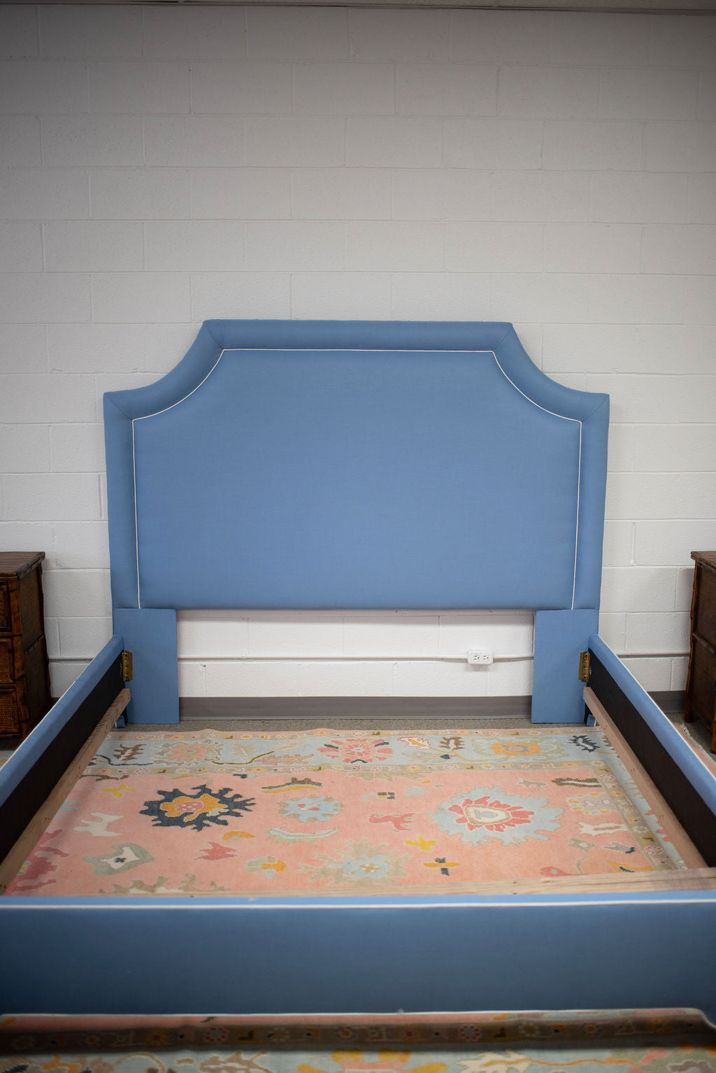 King bed upholstered in blue fabric with white piping