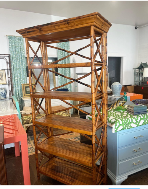 Tortoise bamboo bookshelf in a furniture showroom surrounded by lacquered furniture pieces.