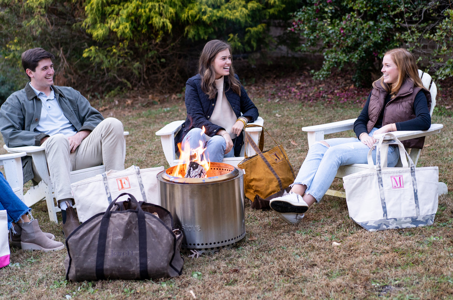 People sitting around a campfire surrounded by Winston's collection canvas and waxed bags 